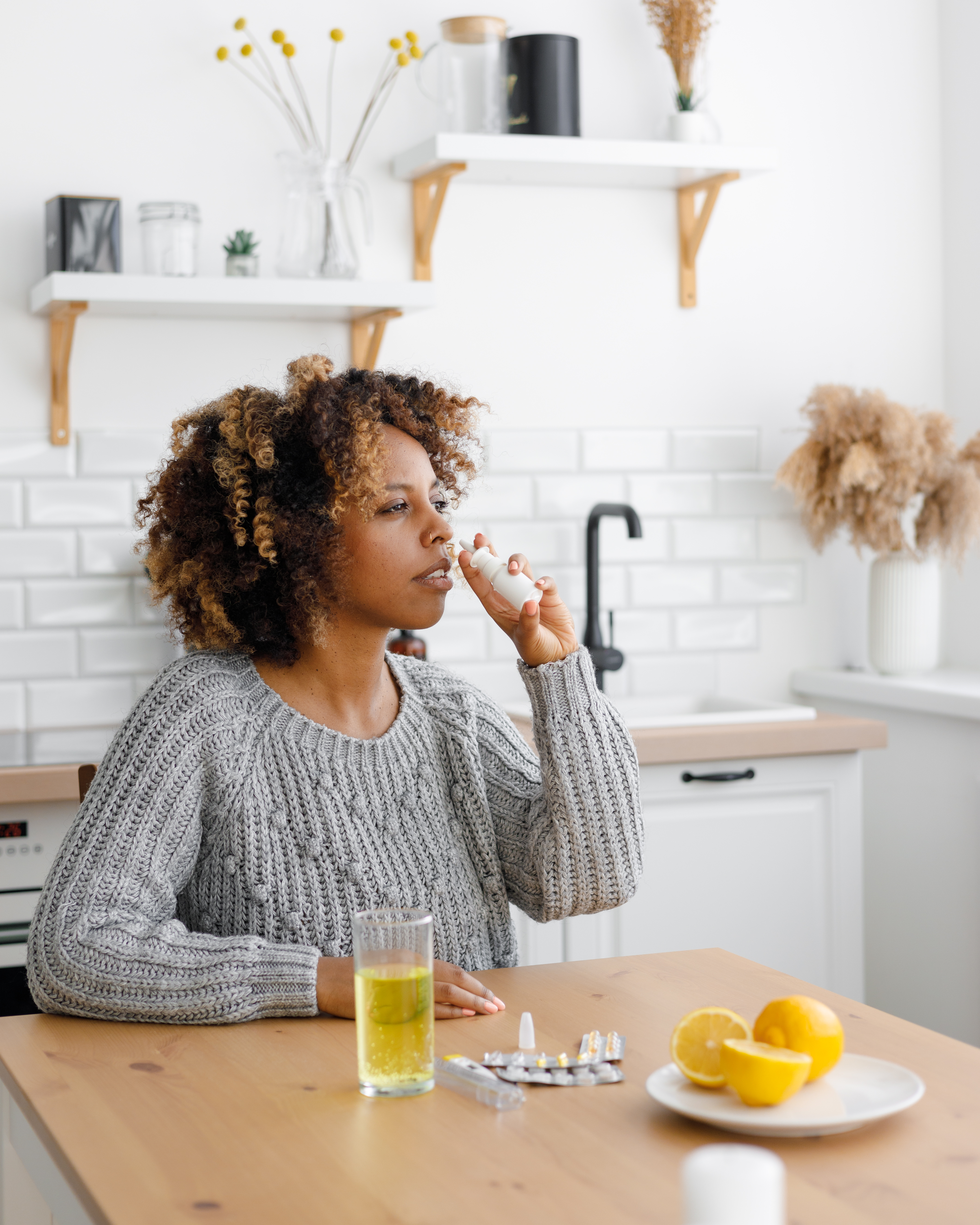 African American woman with a cold, uses a nasal spray. with sore throat, woman with a cold, uses a nasal spray. with sore throat,
